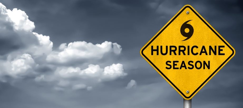 Yellow hurricane season road warning sign in front of dark sky with clouds