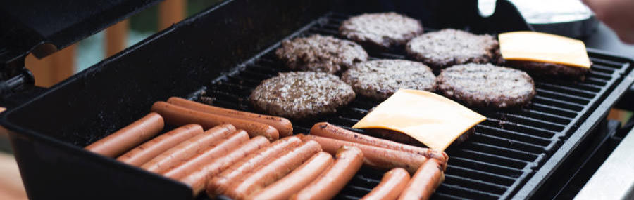 Hotdogs and hamburgers, some with cheese, on a grill