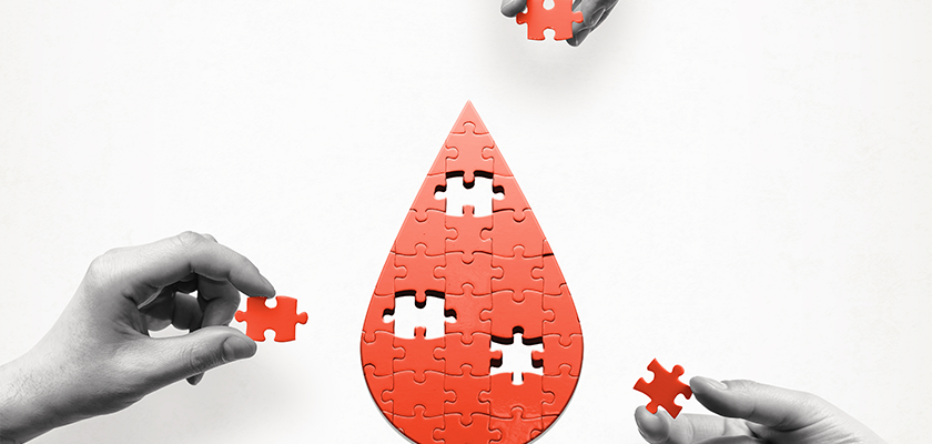 Red puzzle in the shape of a drop of blood has the last three pieces being placed