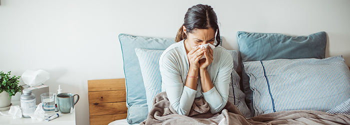 woman sitting in bed sneezing