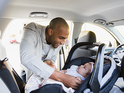 Dad buckling baby into rear-facing car seat