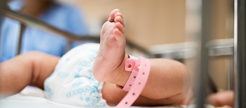 Newborn feet with pink hospital band on left ankle