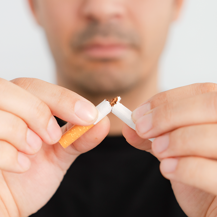 Up close shot of a man snapping a cigarette in half