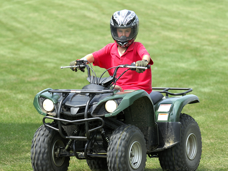 Child riding an ATV wearing a helmet image