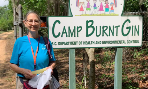 woman in front of camp burnt gin sign