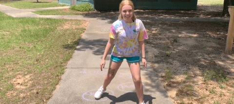 Woman on sidewalk holding chalk image